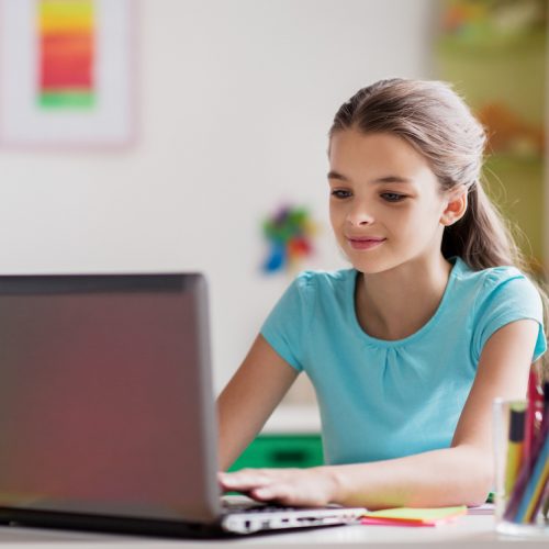 people, children and technology concept - girl typing on laptop computer at home